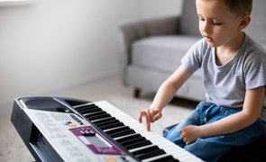 menino com teclado musical aprendendo com a musicalizacao