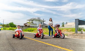 mãe e crianças brincando com triciclos infantis
