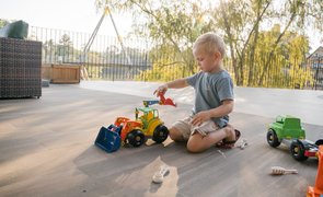 menino ao lado de vários brinquedos para crianças