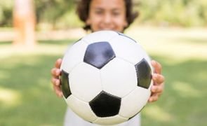 menino segurando bola de futebol