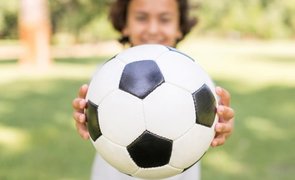 menino segurando bola de futebol
