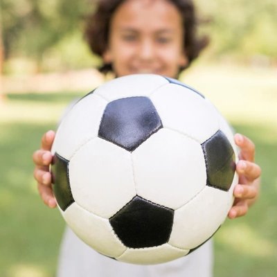 menino segurando bola de futebol