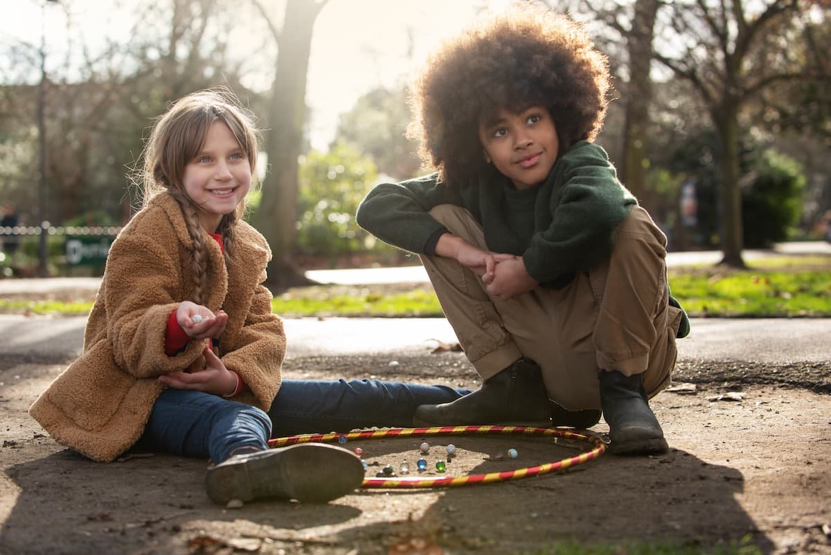 menino e menina jogando bolinhas de gude