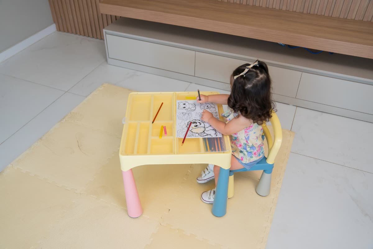 menina pintando em mesinha